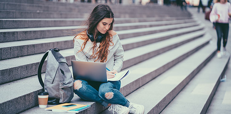 Student sitting on steps with a laptop in her lap