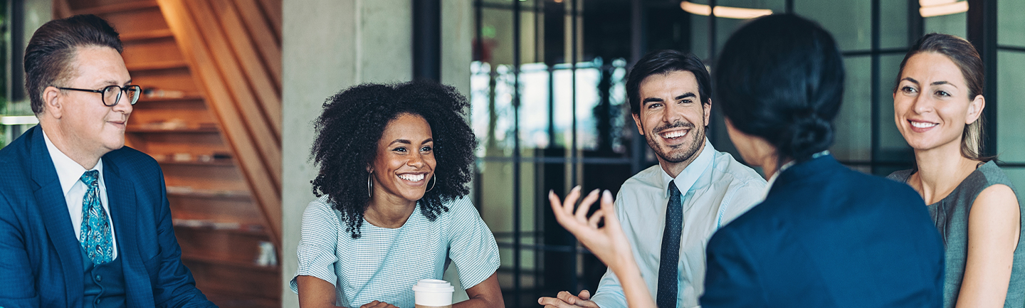 Photograph of a group of working professionals smiling during a meeting